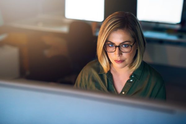 Shot of a young businesswoman working late on a computer in an office